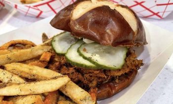 braised pork, bbq, homemade sweet pickles, grain mustard on a pretzel bun